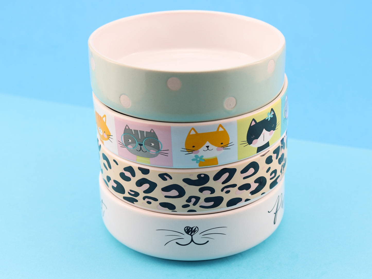 Ceramic cat bowls in four different designs. Sage with polka dots, cute cat portraits, leopard print and white bowl with "purrfect" written on the side with a cat face in the centre of the bowl